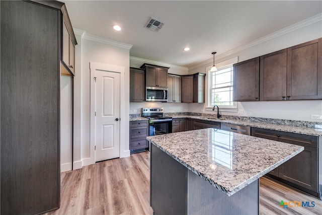 kitchen featuring crown molding, a center island, appliances with stainless steel finishes, decorative light fixtures, and light hardwood / wood-style flooring