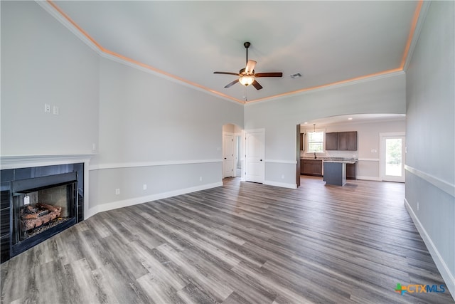 unfurnished living room with dark wood-type flooring, a tile fireplace, and crown molding