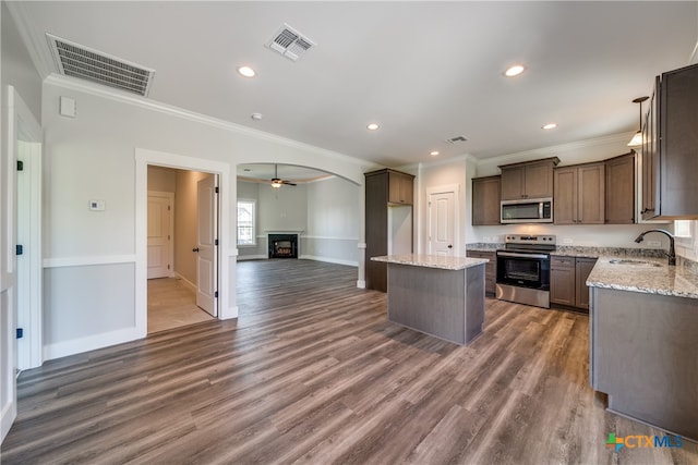 kitchen featuring stainless steel appliances, dark hardwood / wood-style flooring, a center island, sink, and ornamental molding