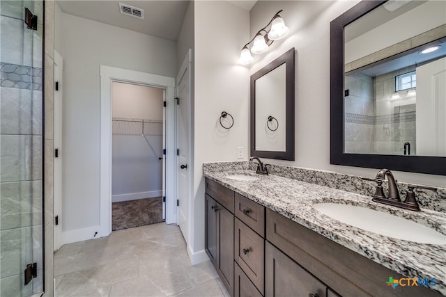 bathroom featuring a shower with door, vanity, and tile patterned floors