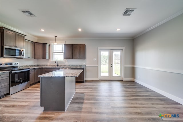 kitchen with hanging light fixtures, light hardwood / wood-style floors, and stainless steel appliances