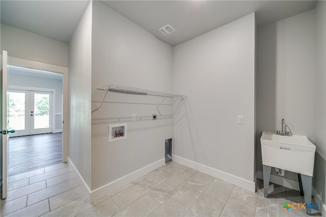 laundry area with hookup for a washing machine, hookup for an electric dryer, light wood-type flooring, and french doors