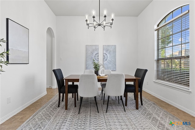 dining room with baseboards, arched walkways, and a notable chandelier