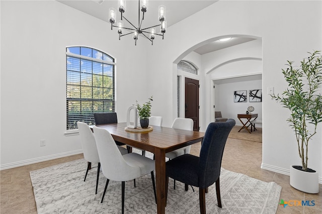dining area featuring arched walkways, light tile patterned flooring, baseboards, and an inviting chandelier