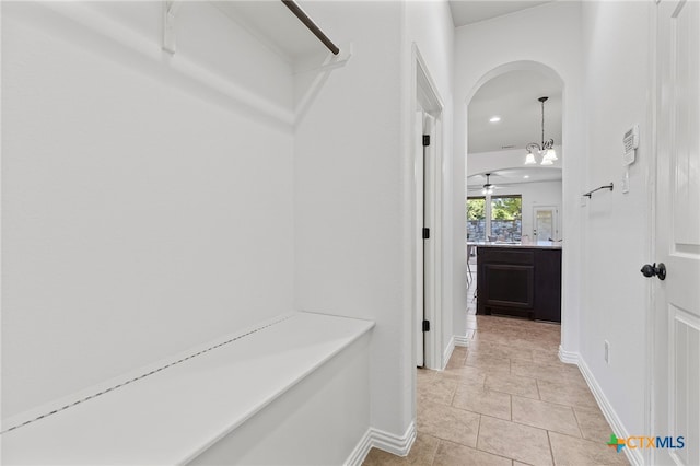 mudroom with light tile patterned floors, baseboards, recessed lighting, and arched walkways