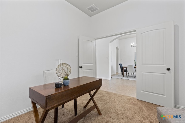 office with light carpet, baseboards, visible vents, and arched walkways