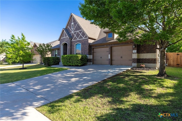 english style home with brick siding, a front yard, fence, and concrete driveway