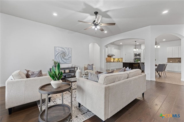 living area featuring recessed lighting, arched walkways, dark wood finished floors, and ceiling fan