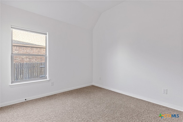 carpeted spare room with baseboards and vaulted ceiling