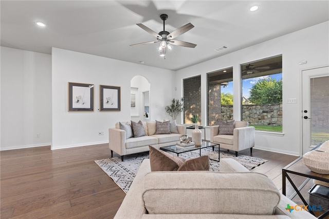 living area featuring ceiling fan, arched walkways, visible vents, baseboards, and hardwood / wood-style flooring