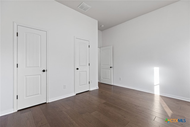 unfurnished bedroom with dark wood-type flooring, baseboards, and visible vents