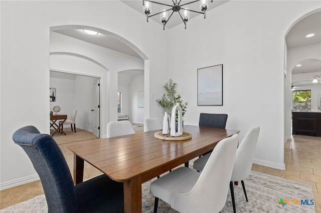 dining space with arched walkways, an inviting chandelier, and baseboards