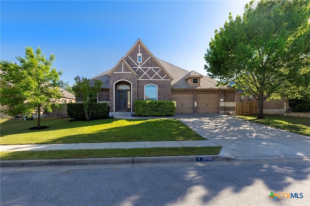 craftsman-style home with brick siding, driveway, fence, and a front lawn