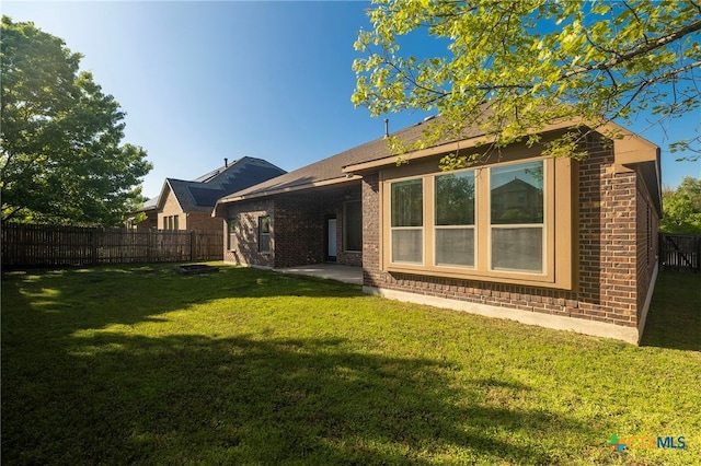back of property with a patio, a yard, fence, and brick siding