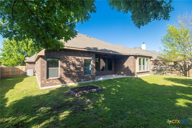 back of property featuring a yard, brick siding, a fenced backyard, and central AC unit