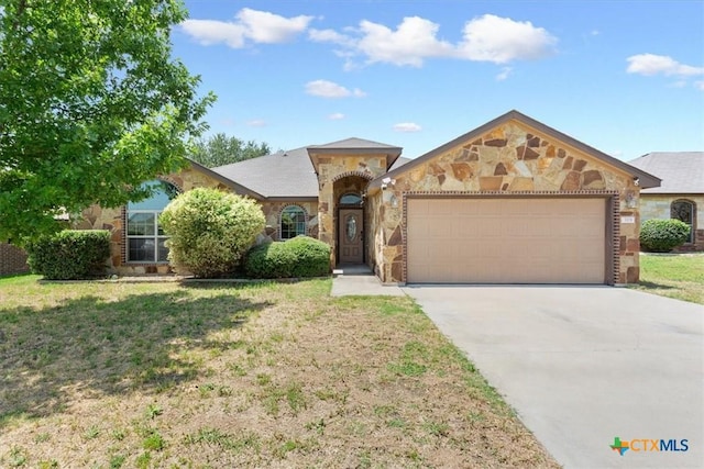 703 Cosper Creek Dr, Killeen, TX 76542 - mediterranean / spanish home featuring stone siding, an attached garage, concrete driveway, and a front lawn