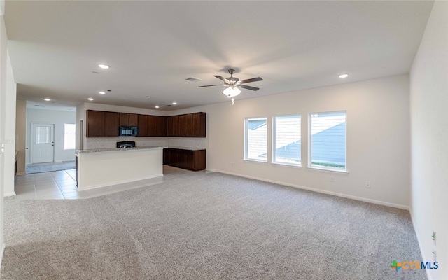 kitchen with a kitchen island, dark brown cabinets, light carpet, and ceiling fan