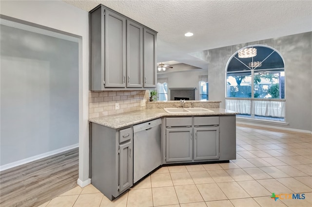 kitchen featuring dishwasher, gray cabinetry, sink, and a textured ceiling