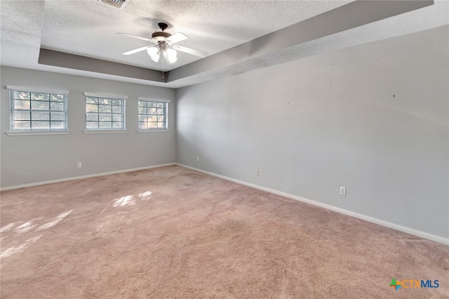 carpeted empty room with a textured ceiling, ceiling fan, and a raised ceiling