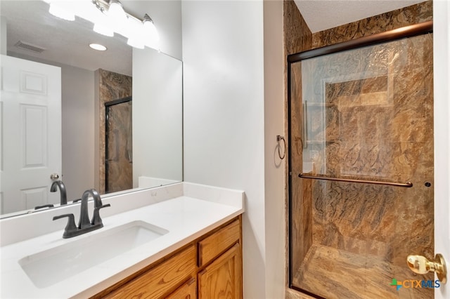 bathroom with walk in shower, vanity, and a textured ceiling