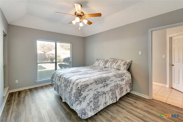 bedroom featuring hardwood / wood-style flooring, ceiling fan, a textured ceiling, and lofted ceiling