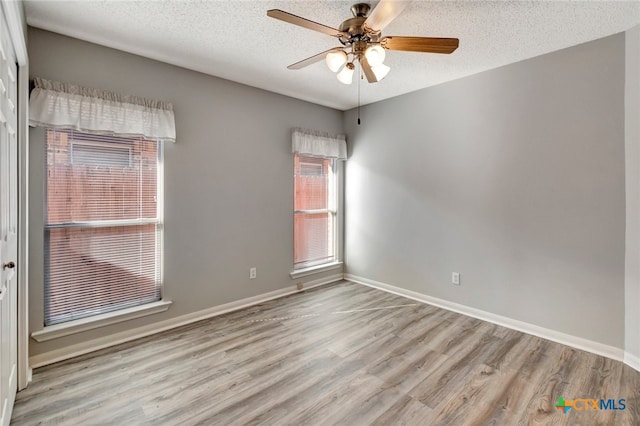 empty room featuring light hardwood / wood-style floors, ceiling fan, and a textured ceiling