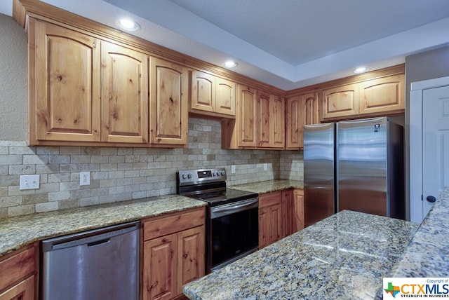 kitchen featuring stainless steel appliances, decorative backsplash, and light stone counters