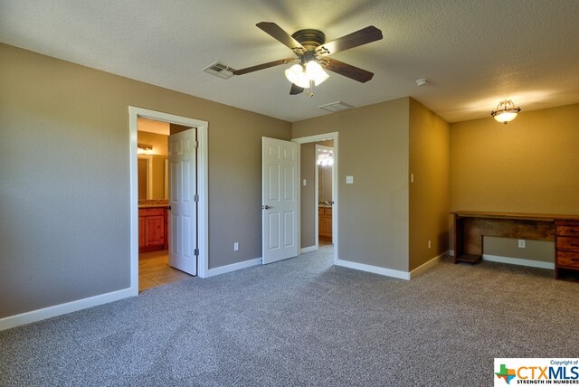 unfurnished bedroom featuring ceiling fan, ensuite bath, light carpet, and a textured ceiling