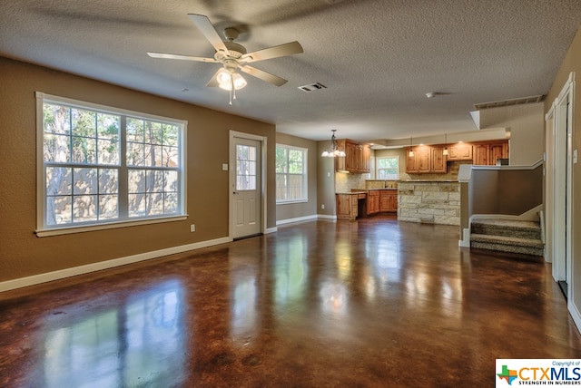 unfurnished living room featuring a textured ceiling and ceiling fan with notable chandelier