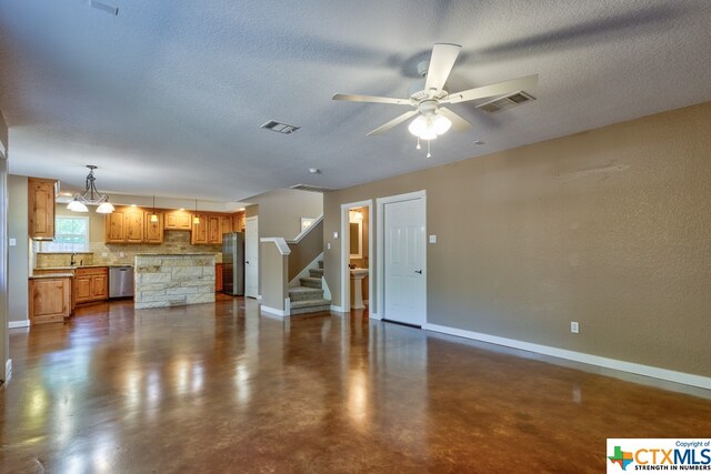 unfurnished living room with ceiling fan with notable chandelier and a textured ceiling