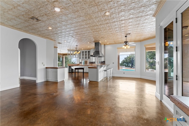 unfurnished living room featuring ceiling fan and ornamental molding