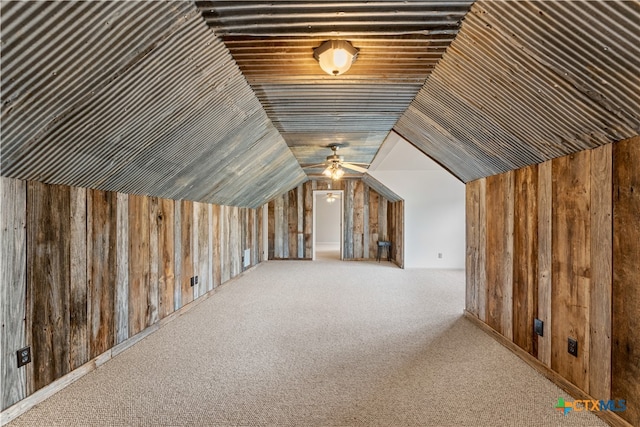 additional living space with ceiling fan, wooden walls, light carpet, and lofted ceiling