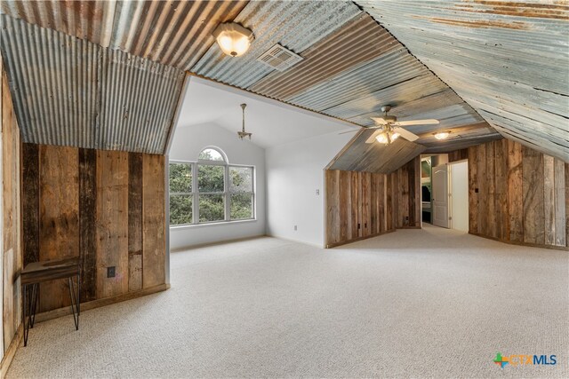 bonus room with wood walls, ceiling fan, lofted ceiling, and light colored carpet