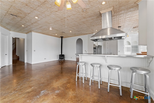 kitchen with island exhaust hood, a breakfast bar area, kitchen peninsula, and stainless steel refrigerator