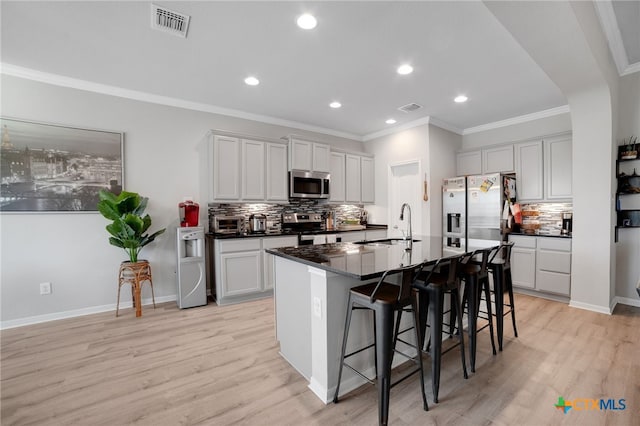 1444 Rolling Brook Dr, Temple, TX 76502 - kitchen featuring appliances with stainless steel finishes, dark countertops, a sink, decorative backsplash, and a kitchen breakfast bar