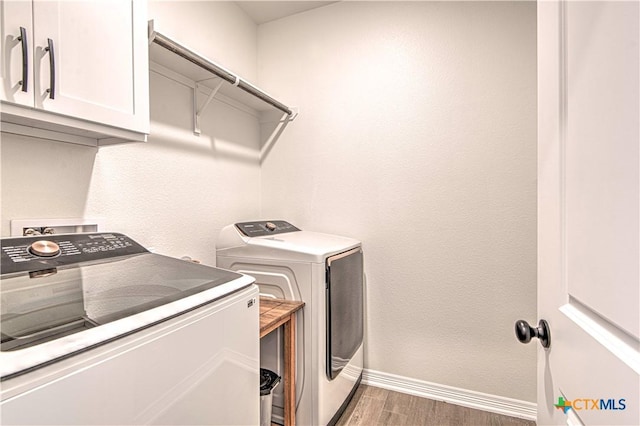 washroom featuring cabinets, dark hardwood / wood-style floors, and washer and clothes dryer