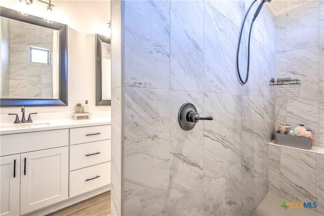 bathroom with vanity, hardwood / wood-style flooring, and tiled shower