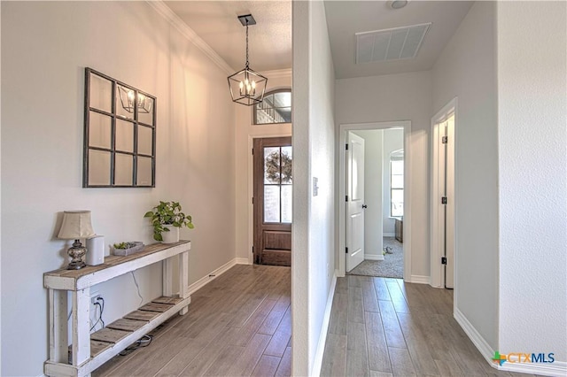 entrance foyer with an inviting chandelier, hardwood / wood-style floors, and crown molding