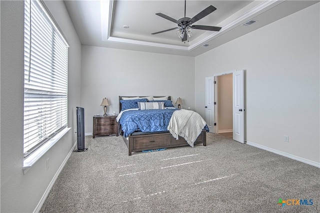 bedroom featuring multiple windows, a tray ceiling, ceiling fan, and carpet