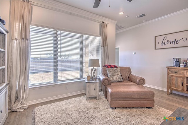 sitting room with ceiling fan, ornamental molding, and light wood-type flooring