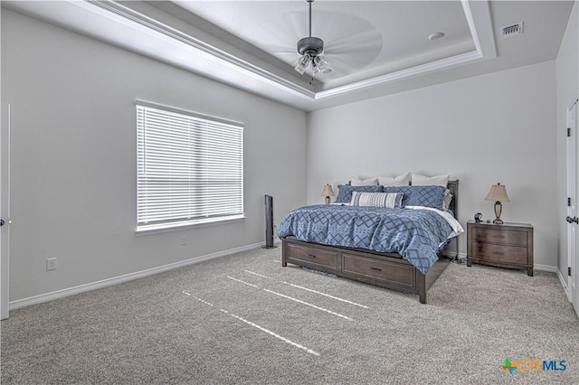 bedroom with light colored carpet, a raised ceiling, and ceiling fan