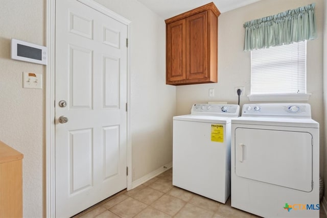 clothes washing area featuring cabinets, washing machine and dryer, and light tile patterned floors