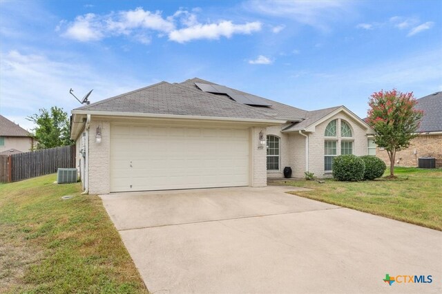 ranch-style home featuring a front lawn, central air condition unit, and a garage