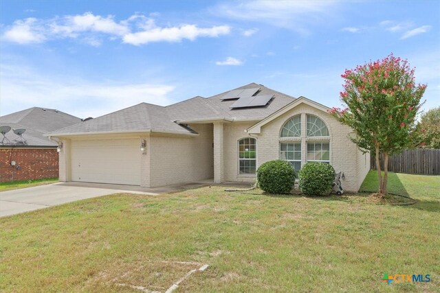 view of front of house featuring a front lawn, a garage, and solar panels