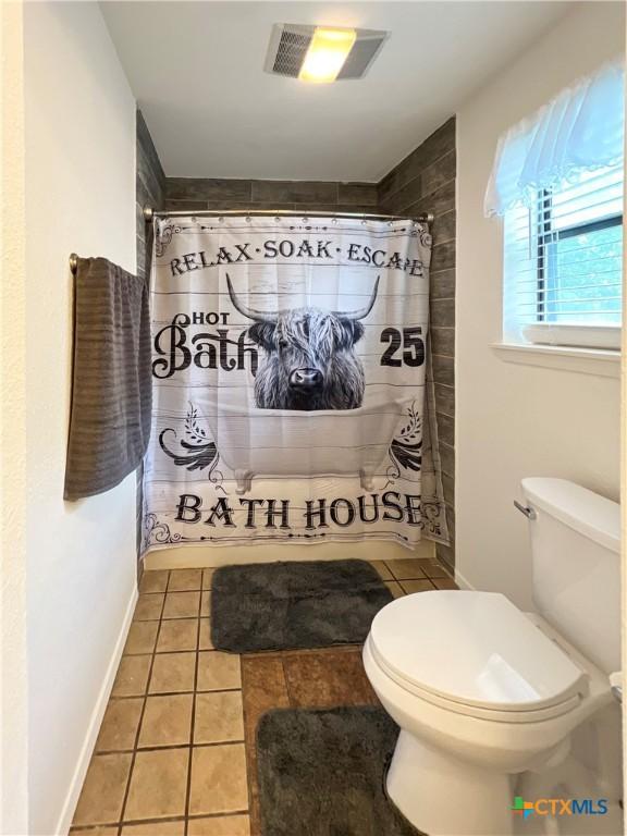 701 Clark St, Gonzales, TX 78629 - bathroom with toilet, tiled shower, tile patterned flooring, and baseboards
