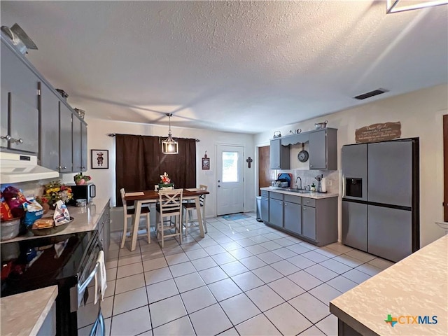 701 Clark St, Gonzales, TX 78629 - kitchen with under cabinet range hood, appliances with stainless steel finishes, light countertops, light tile patterned floors, and a sink