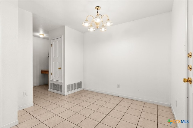 tiled spare room featuring a chandelier