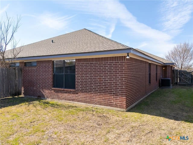 view of side of home featuring central AC unit and a yard