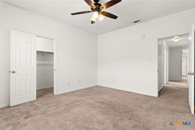 unfurnished bedroom with a spacious closet, ceiling fan, a closet, and light colored carpet