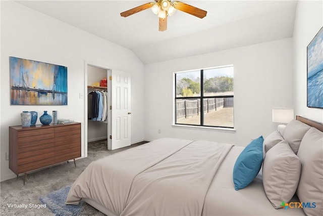 bedroom with ceiling fan, lofted ceiling, carpet flooring, a walk in closet, and a closet